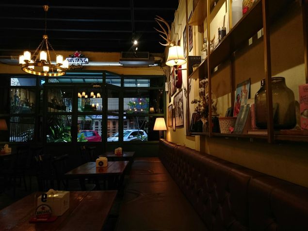 Een schemerige restaurantzaal in de avond, met een kroonluchter boven de tafels.