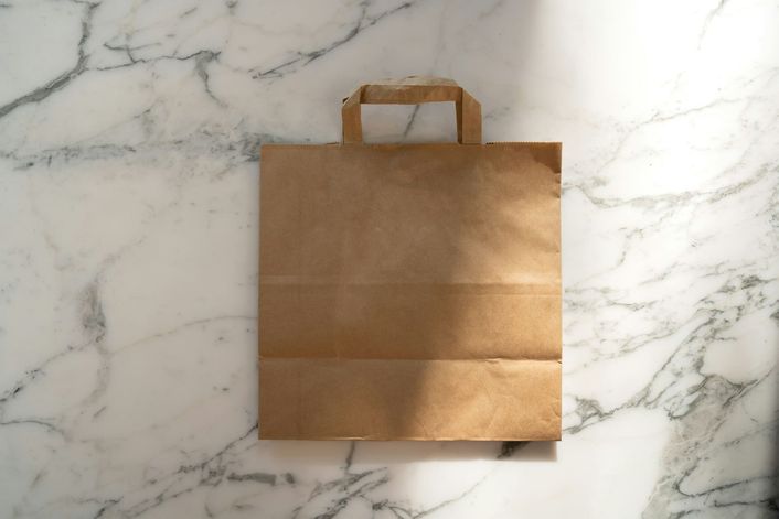 A brown paper takeaway bag on a marble surface.